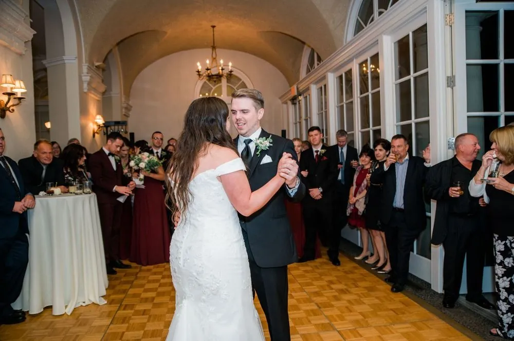 The couple shares a first dance on the parquet floor as guests ring the room