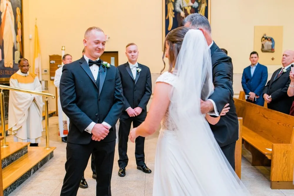 Groom and a groomsman wait at the church altar as the bride comes up the aisle