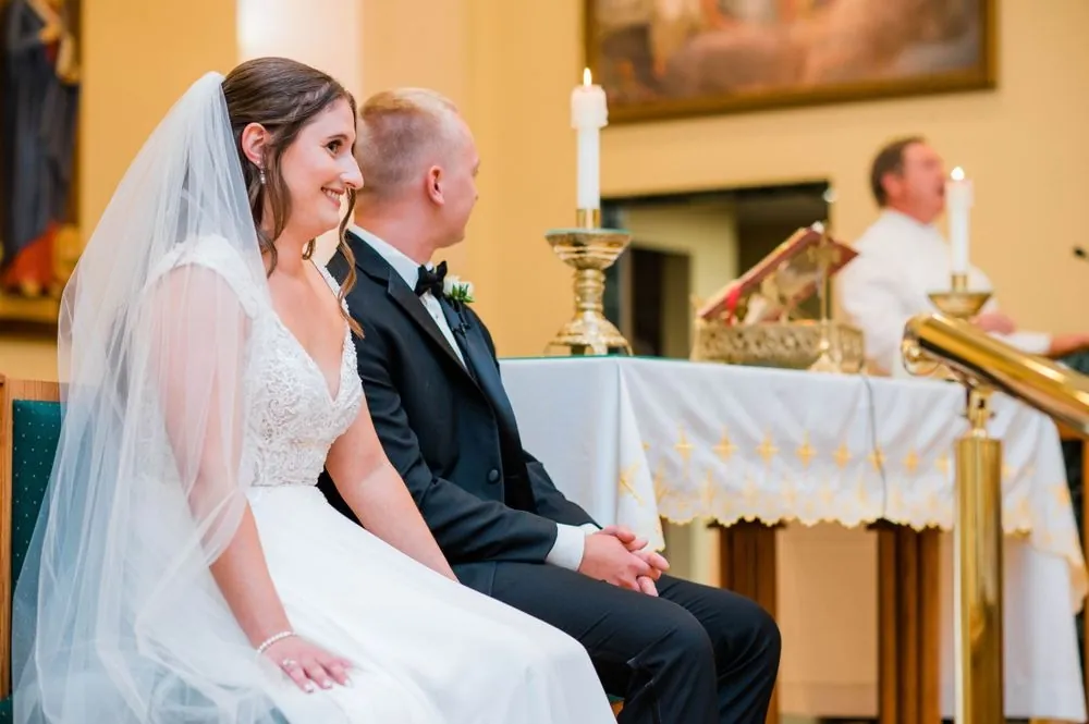 Michelle and Matt sit side by side before the altar, candles and linens behind them