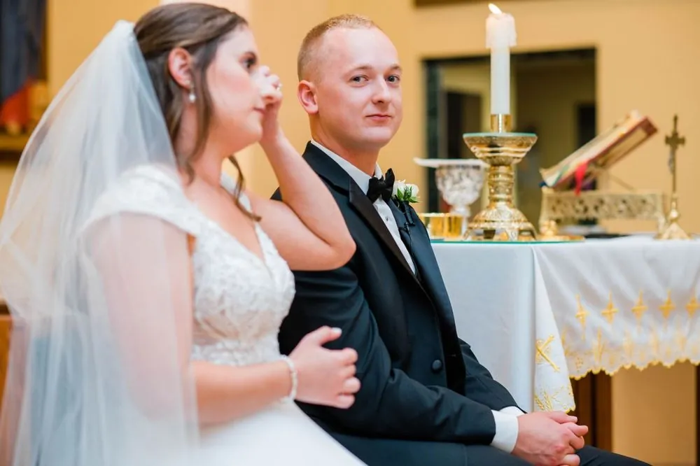 Bride wipes a tear as the groom sits beside her during the church ceremony