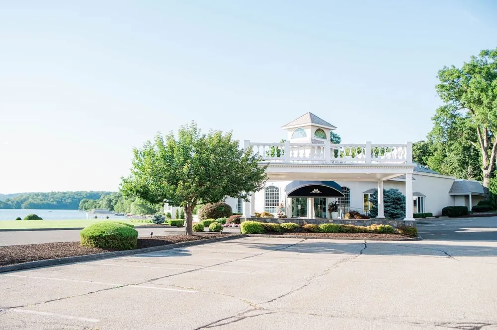 White Candlewood Inn with its cupola and portico beside the lake on a clear day