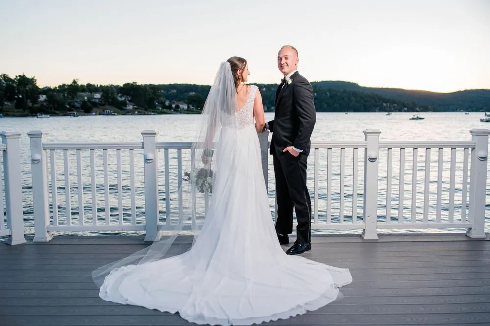 Michelle and Matt stand at the white deck railing looking over the lake at dusk