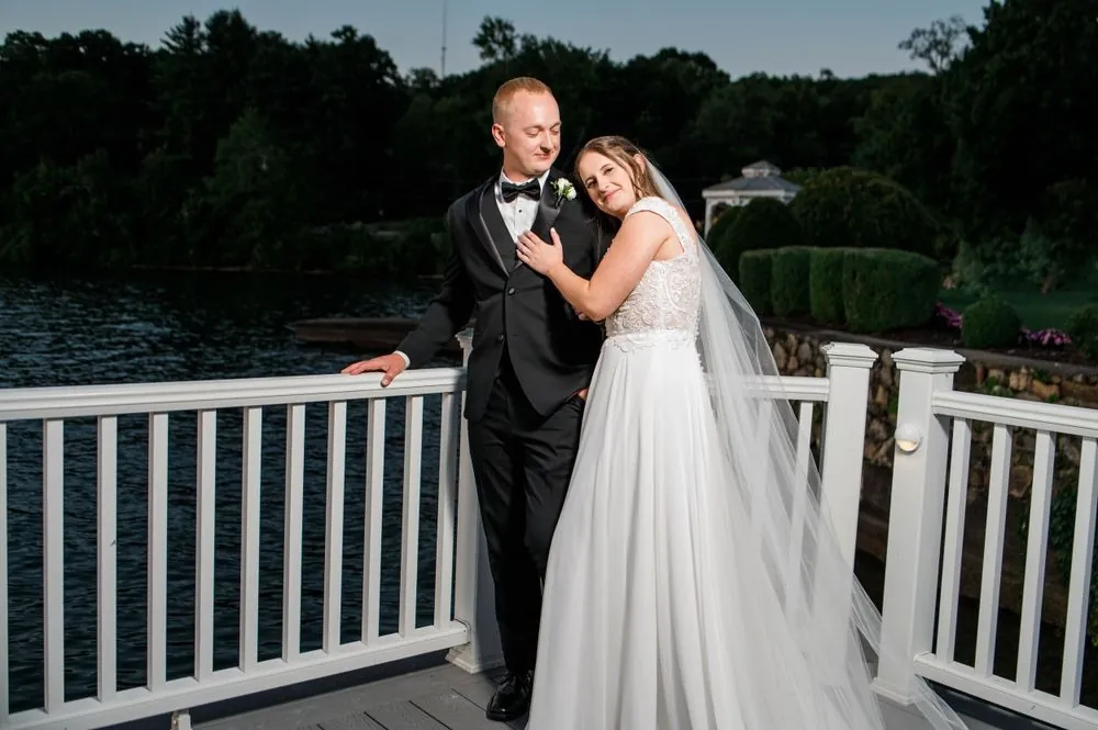 Michelle leans into Matt against the deck railing as night falls over the water