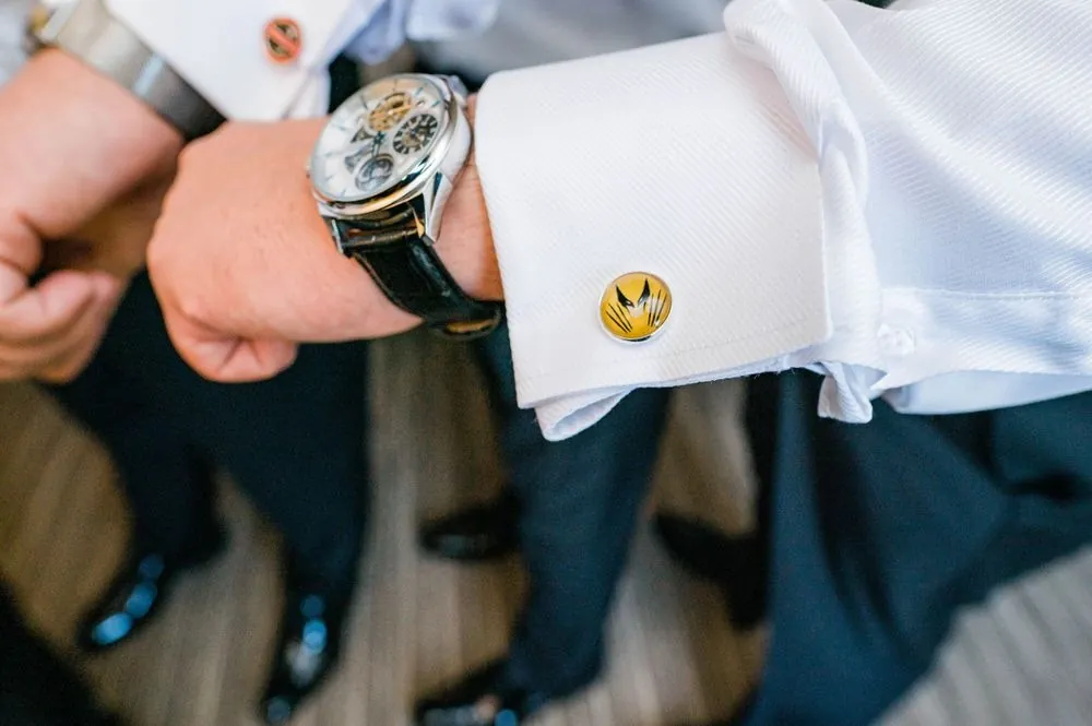 Close view of a cufflink and wristwatch on a white shirt sleeve