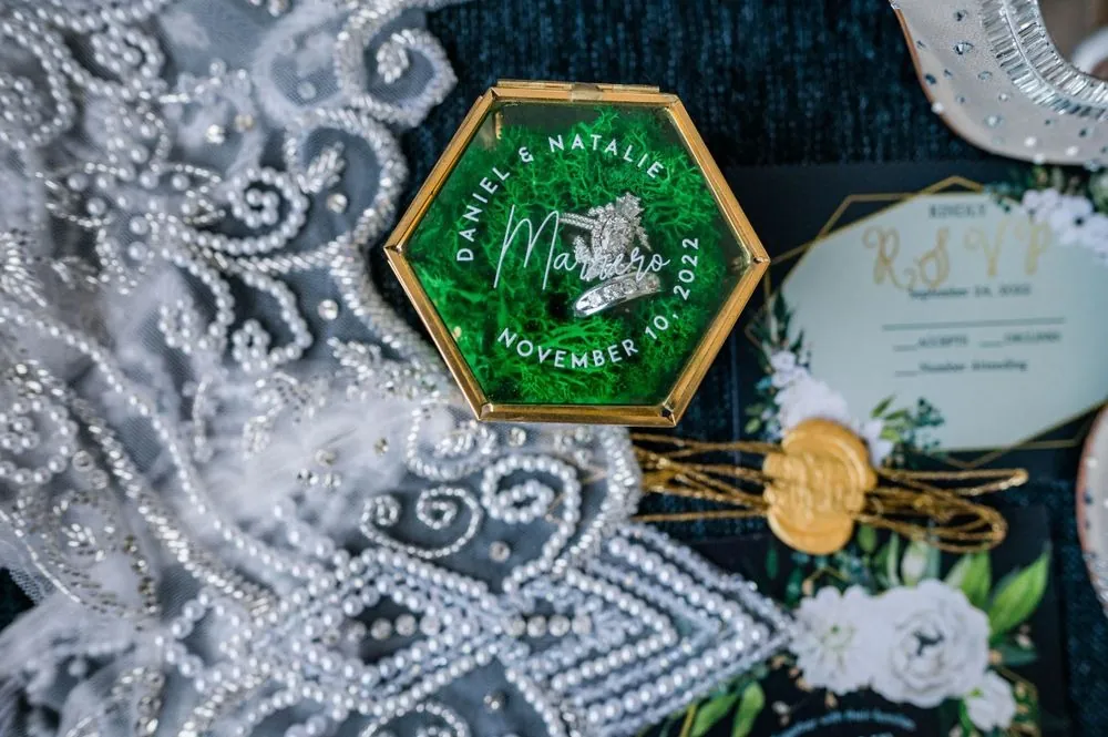 A green hexagon wax seal on the invitation, set on beaded lace