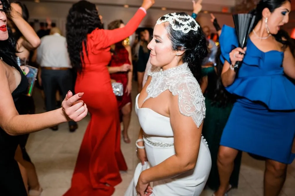 The bride dances among guests in bright dresses on a crowded floor
