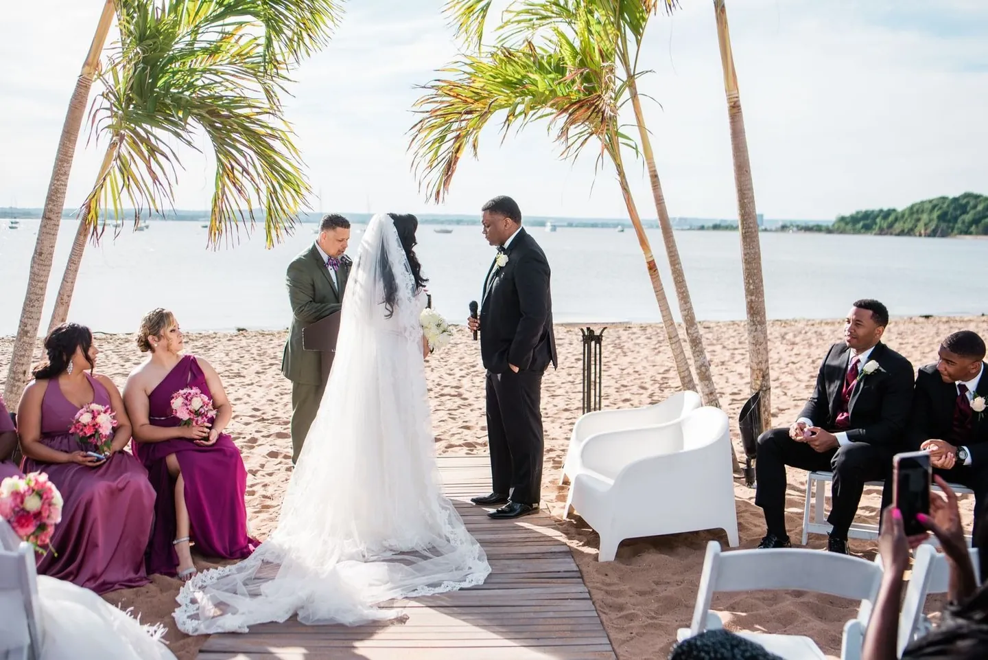 Natasha and Jordan face each other on the boardwalk between palm trees and open water