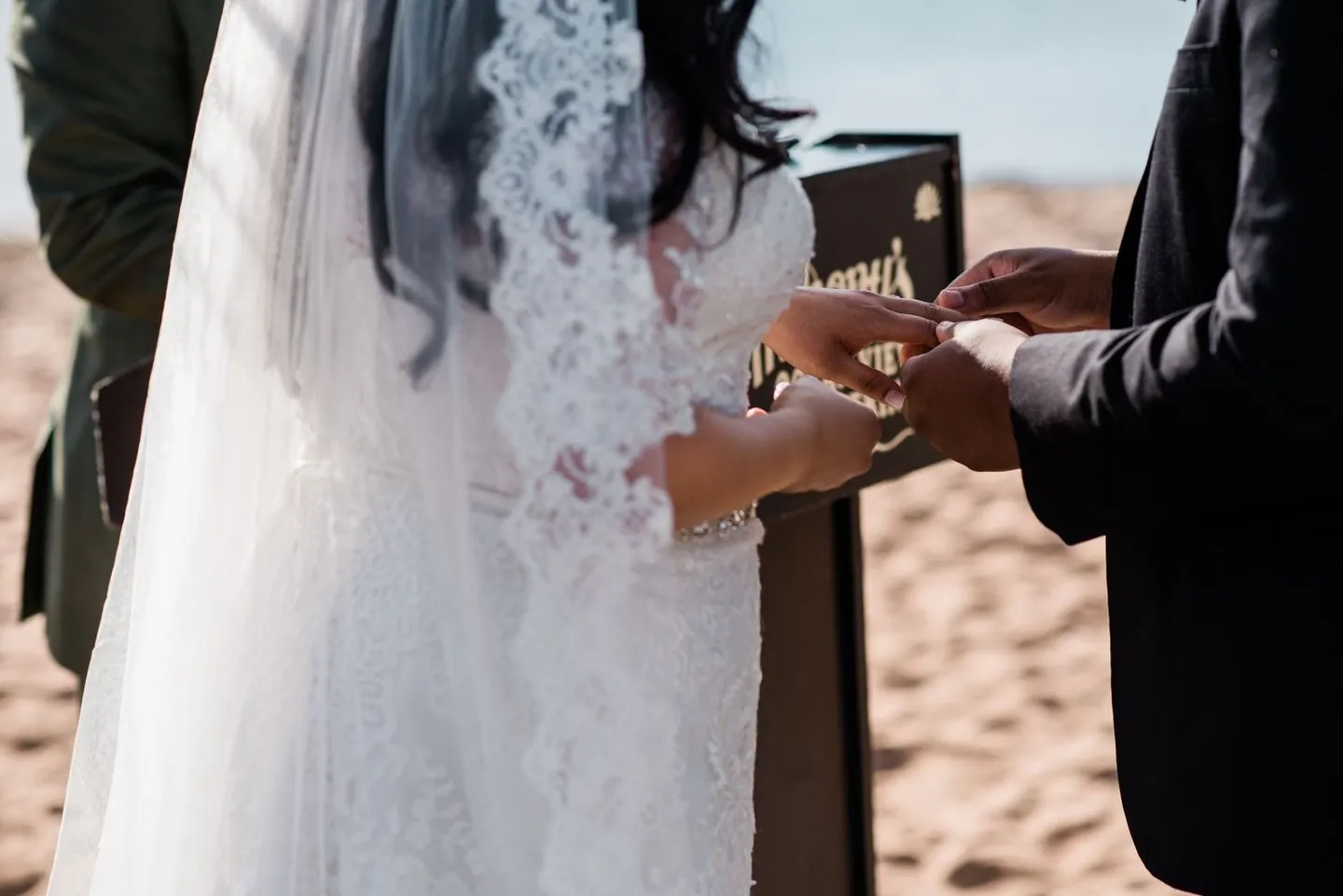 Close view of hands sliding a ring on during the beach ceremony