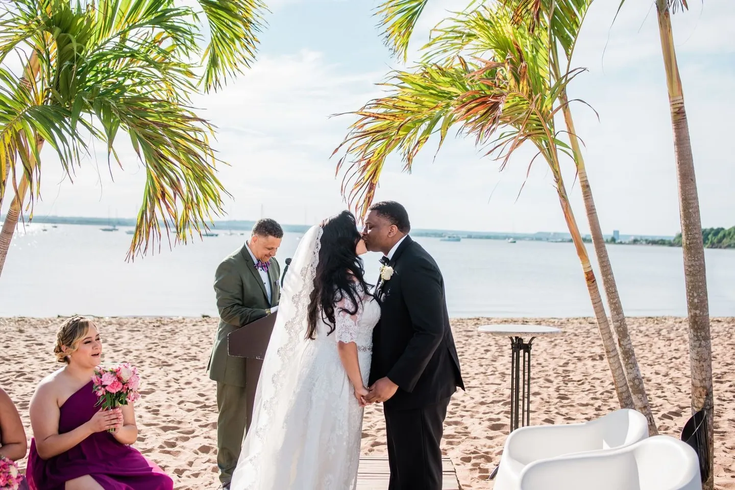 Natasha and Jordan kiss on the boardwalk under palm trees as bridesmaids watch