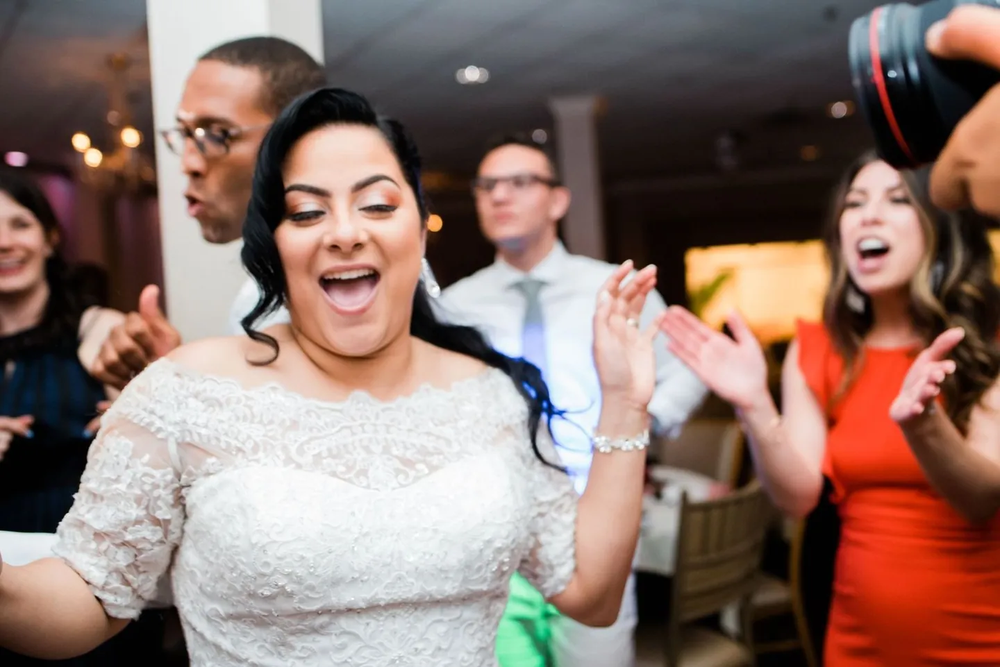 Bride laughs and dances with guests in bright dresses on the crowded floor