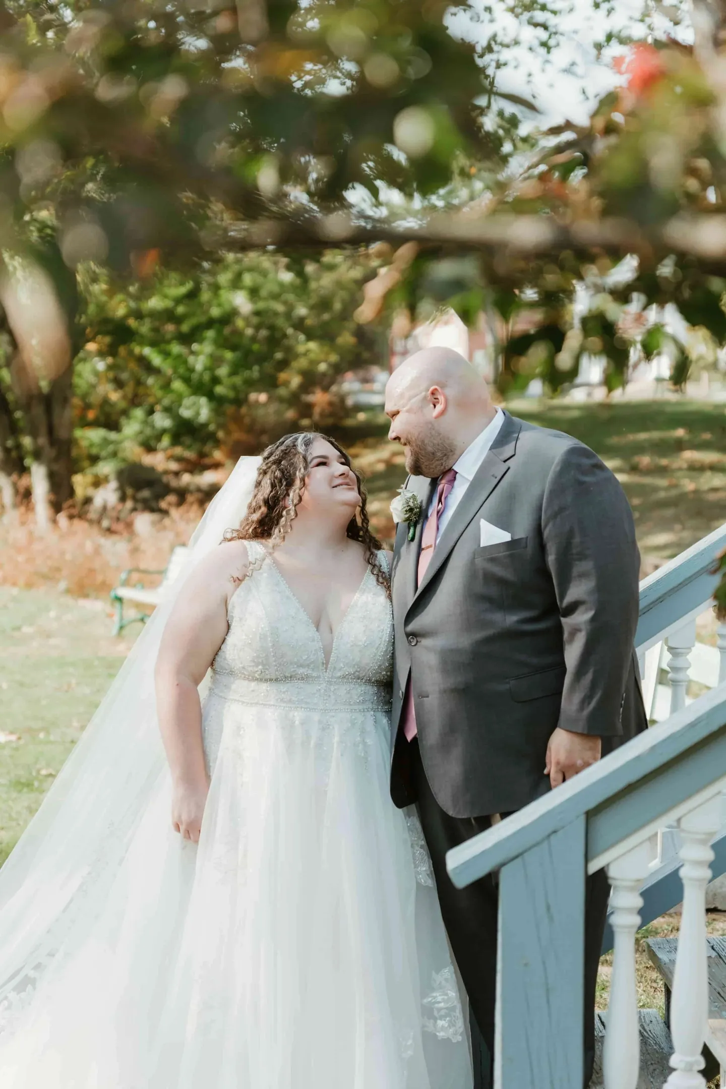 Nicole and Ryan share a quiet moment at a white railing under turning leaves