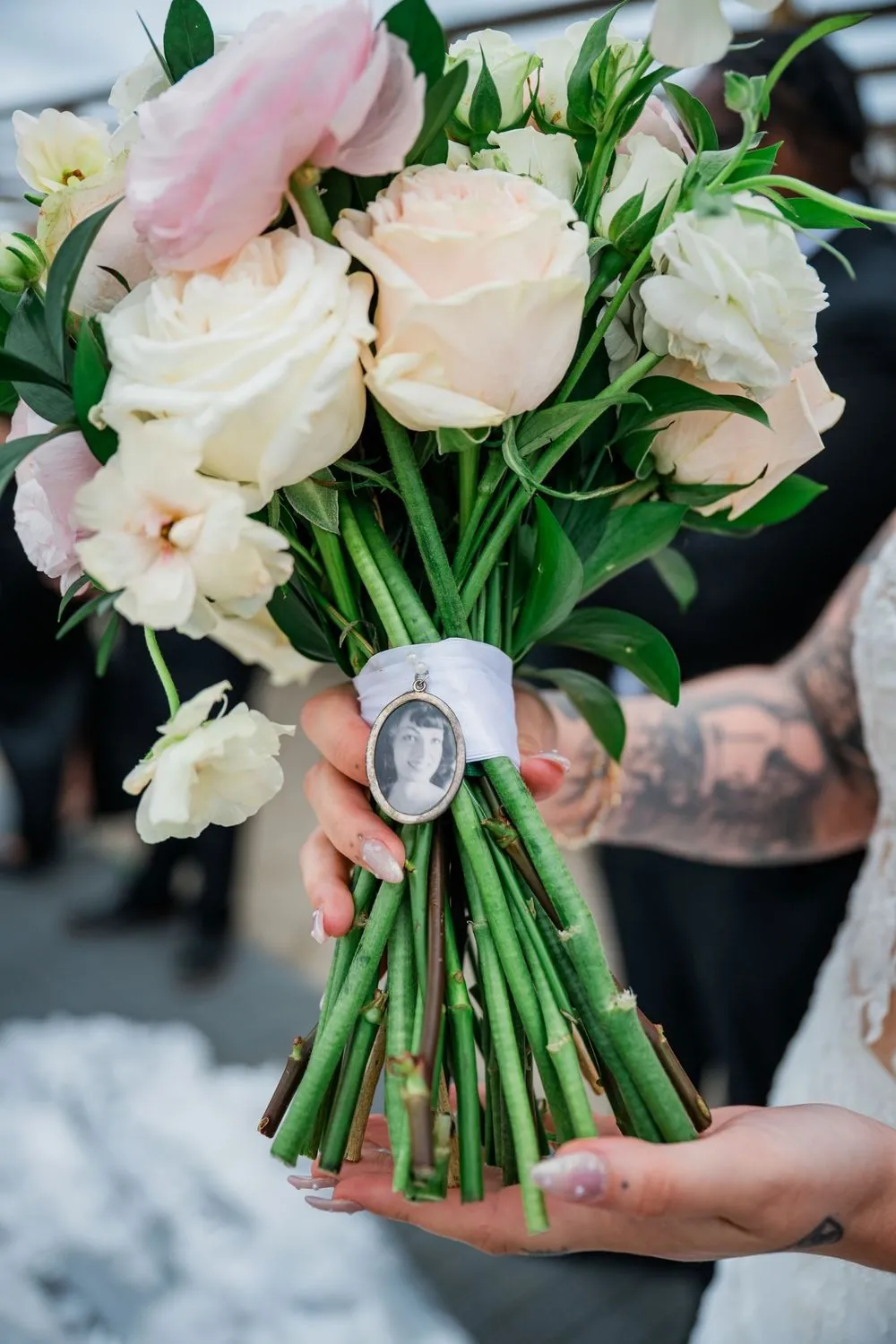 Blush and ivory rose bouquet with a small photo charm wrapped around the stems
