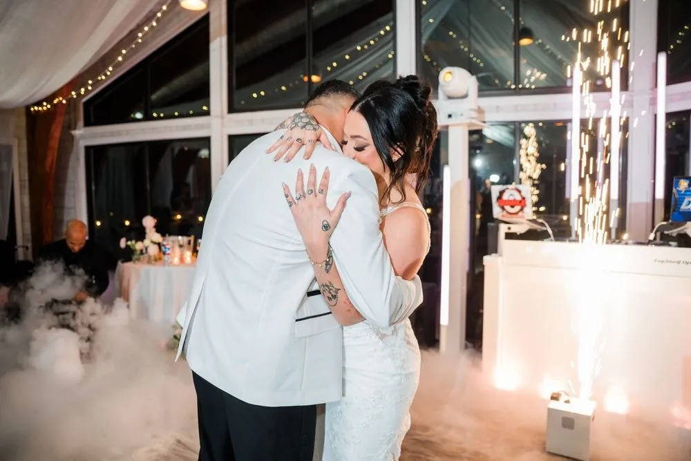 Olivia and Elvin slow dance in low fog as cold sparks shoot up beside the DJ booth