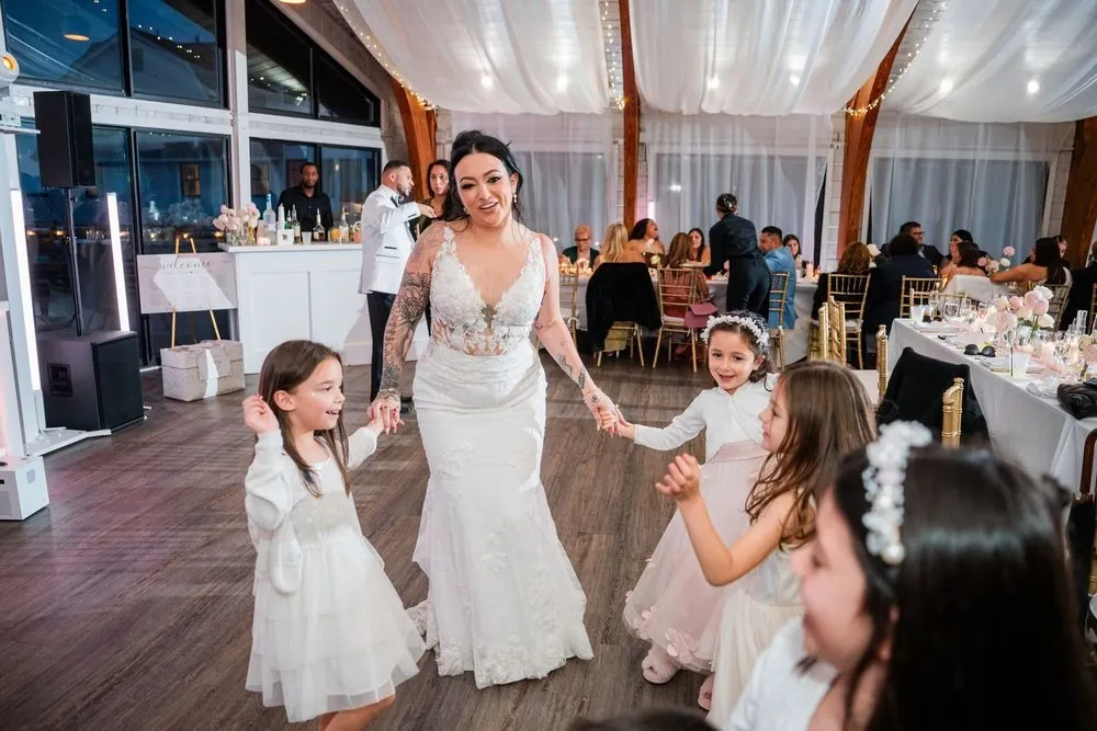 Flower girls in white dresses spin the bride around the pavilion dance floor