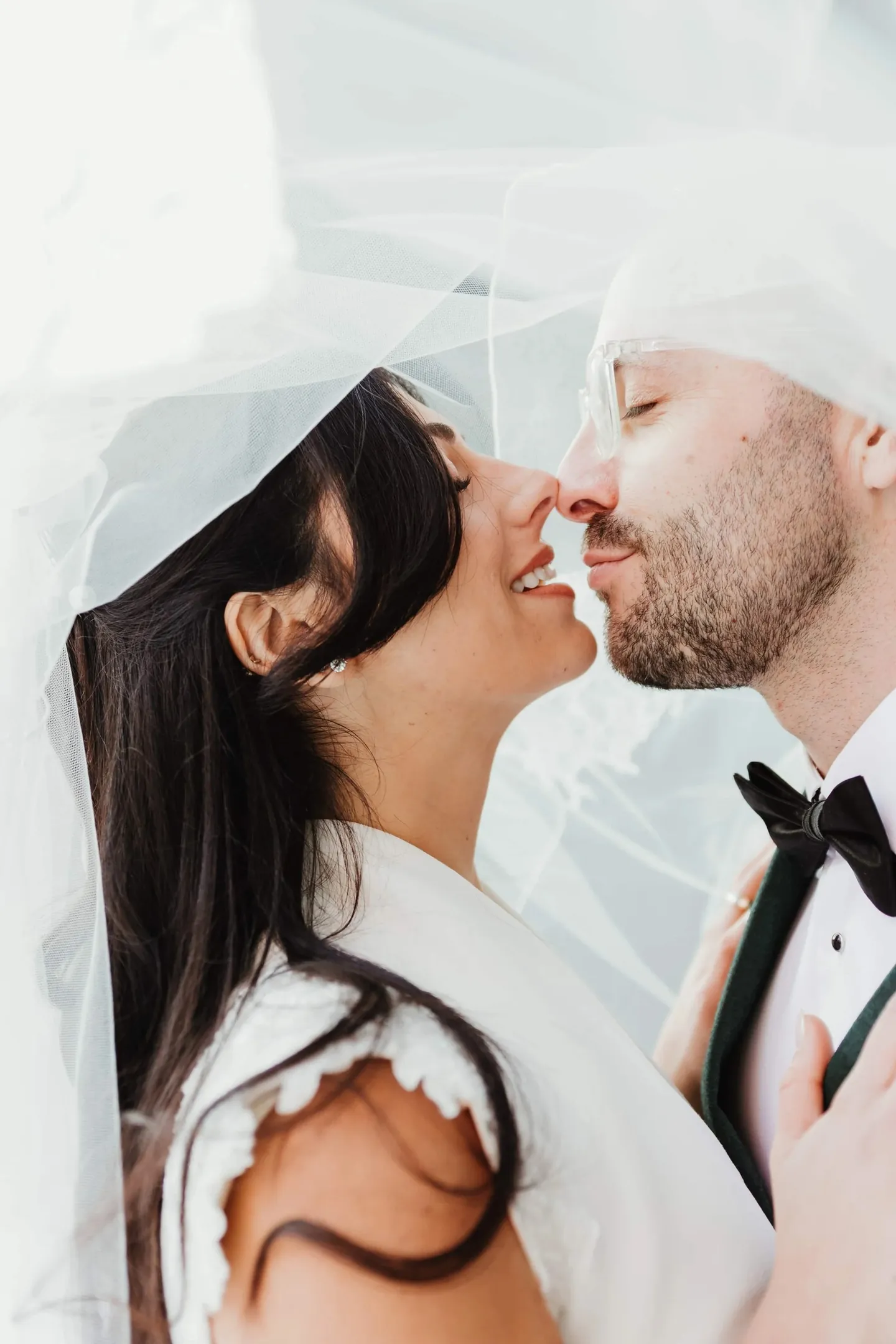 Rachel and Joe share a close, smiling moment under the sheer veil