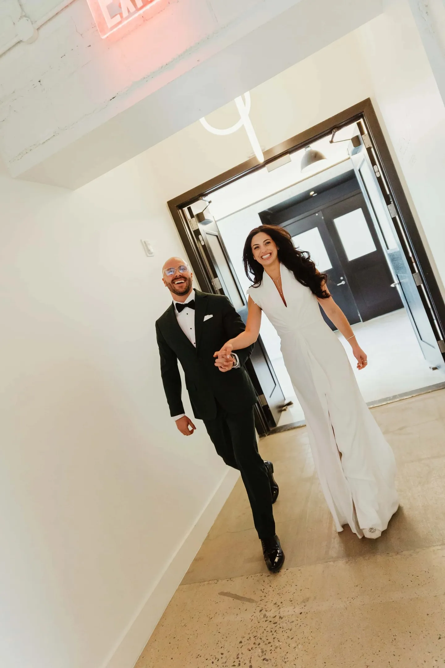 Rachel and Joe hurry hand in hand through dark doors into the reception