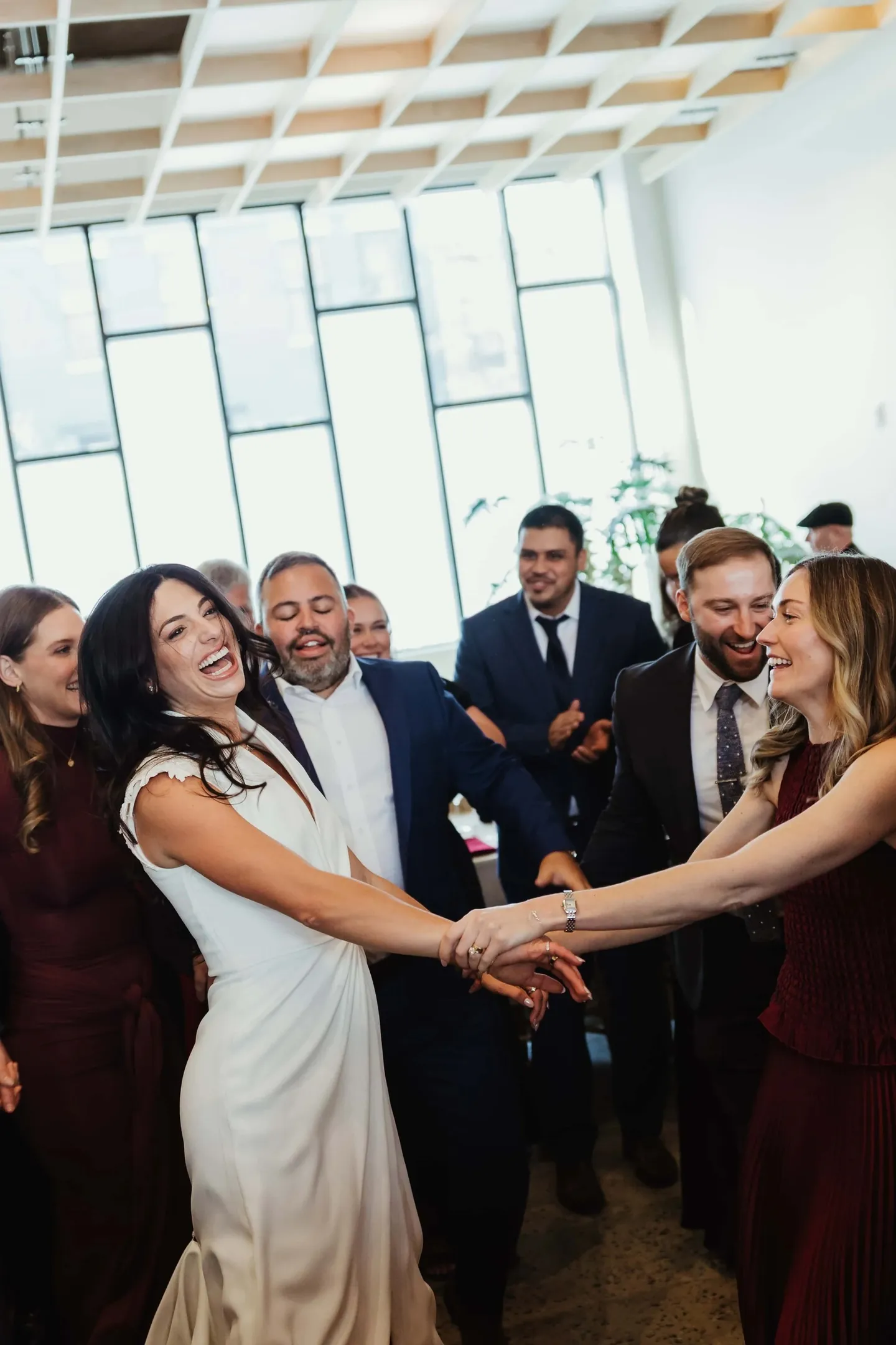 The bride dances in a circle holding hands with laughing guests