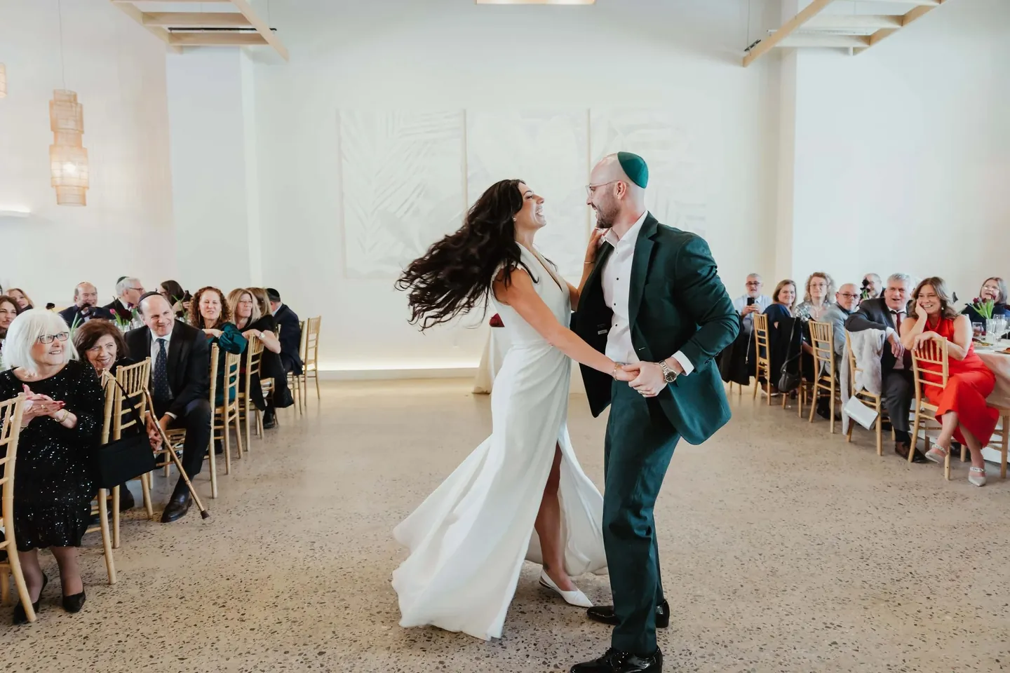 Rachel and Joe spin across the floor as seated guests watch from the long tables