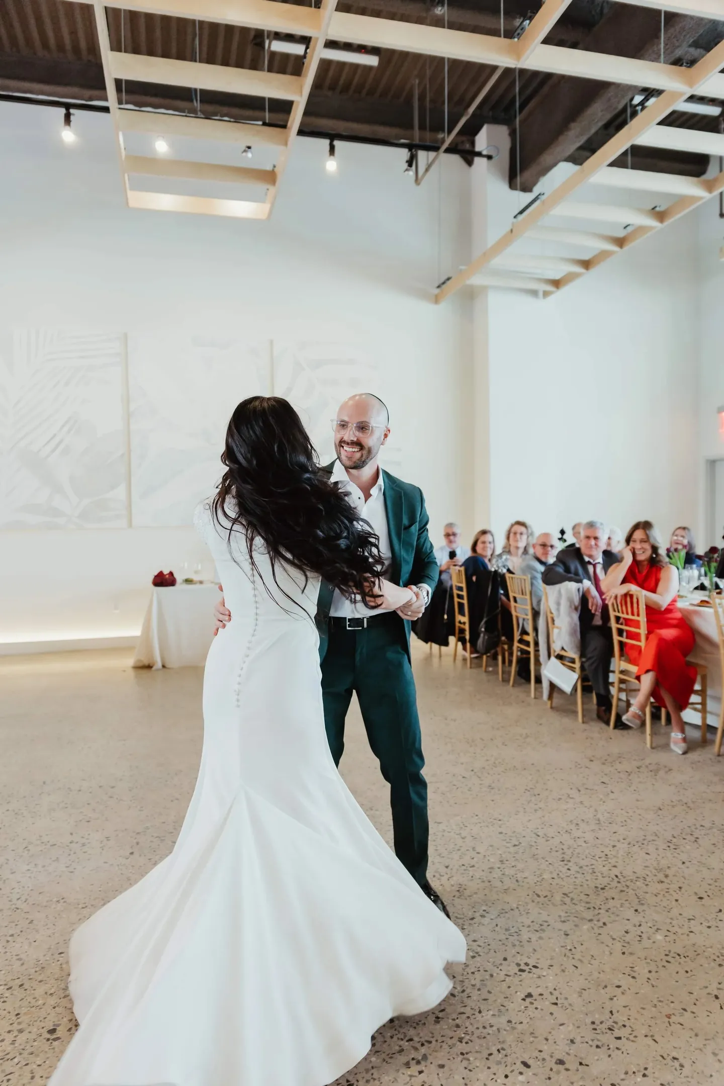 Rachel and Joe dance close at the end of the room beneath wooden ceiling slats