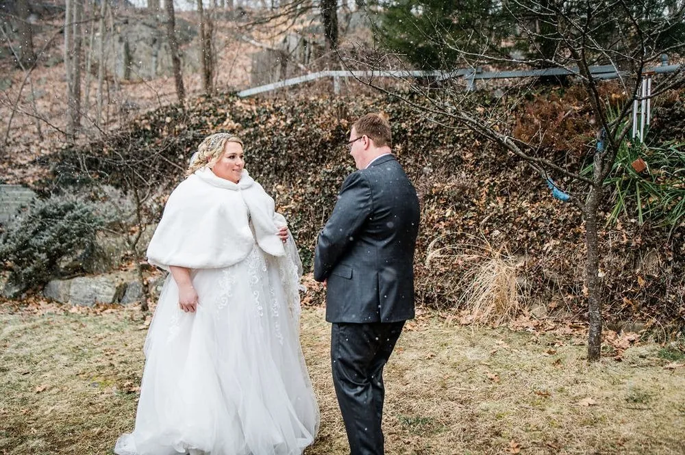 Sandra turns to Daniel for their first look in a wooded backyard as snowflakes fall