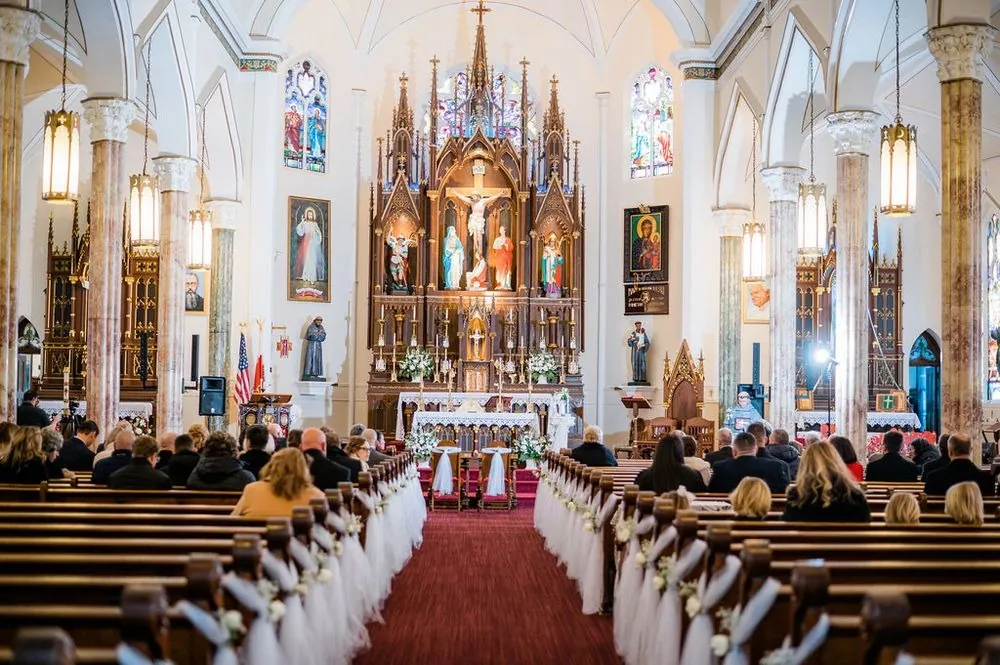 The church aisle lined with white tulle pew bows leads to a towering carved altar