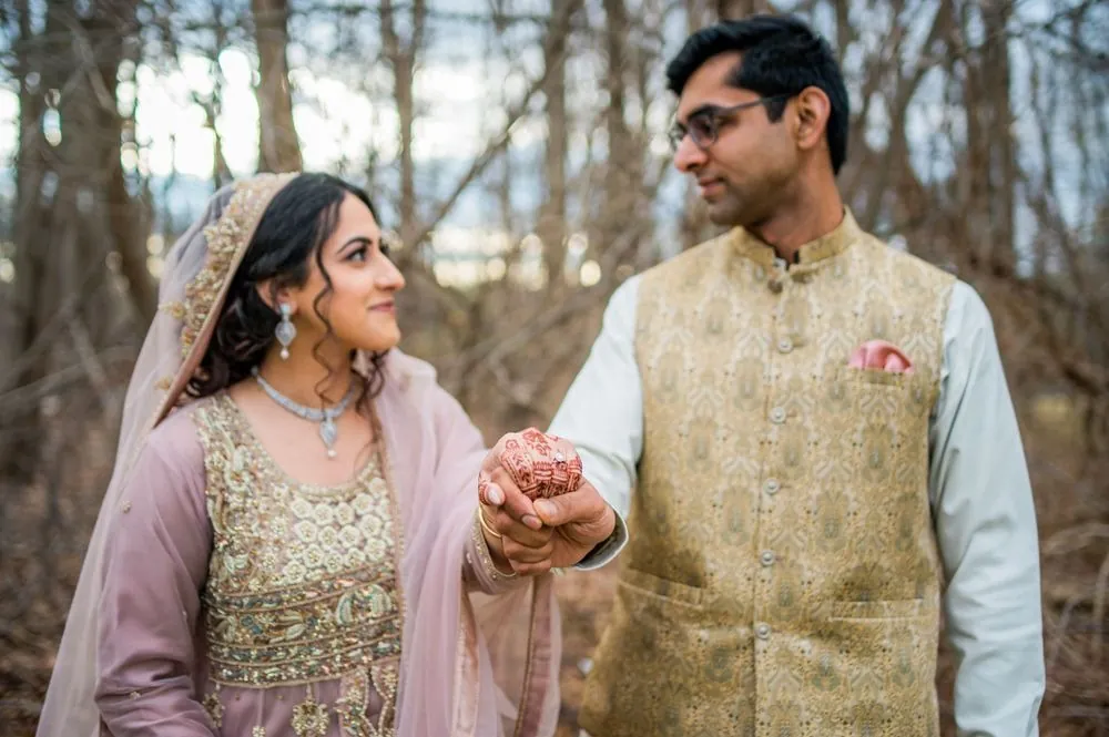 Qaniat and Sohaib hold hands between them, her henna and ring in sharp focus