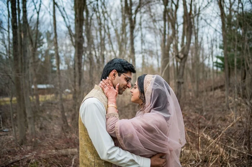 Qaniat rests a hennaed hand on Sohaib's cheek as they lean close in the woods