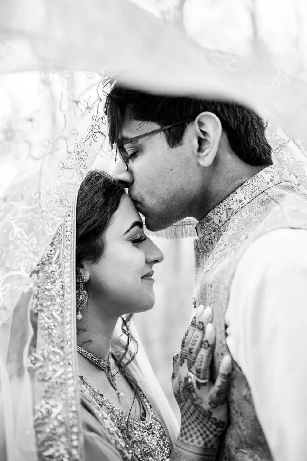 Sohaib kisses Qaniat's forehead as she closes her eyes, in black and white