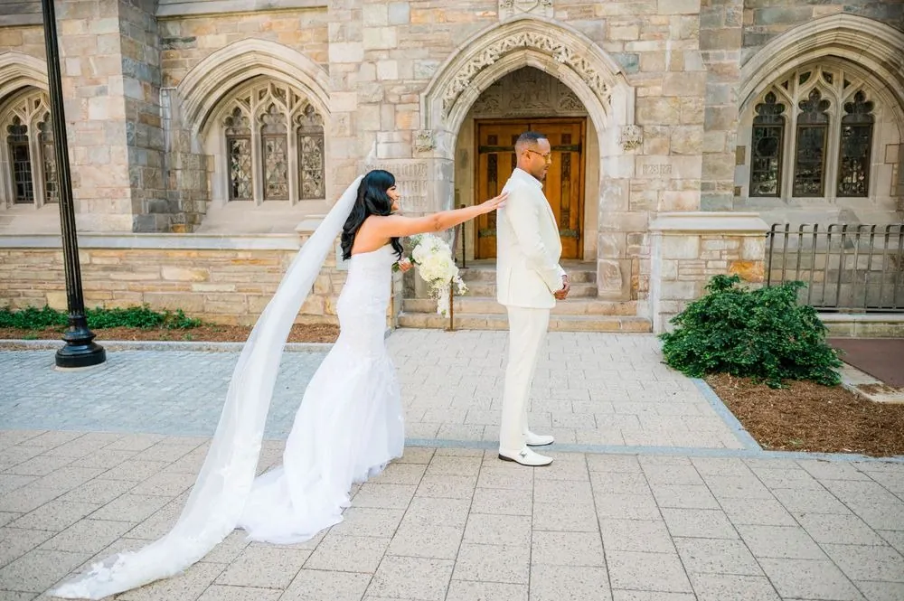Sollisa reaches for DJ's shoulder during their first look outside a carved Gothic stone doorway