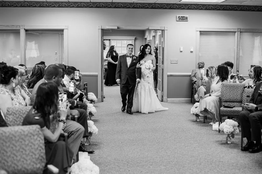 Guests turn toward the doorway as the bride enters the ceremony room, in black and white