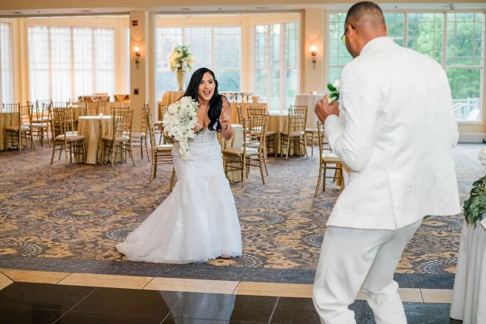 DJ dances toward Sollisa across the ballroom floor as she holds her bouquet