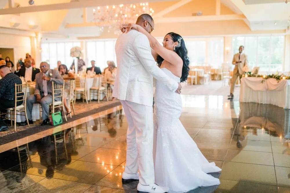 Sollisa and DJ share their first dance on a glossy floor below tall windows