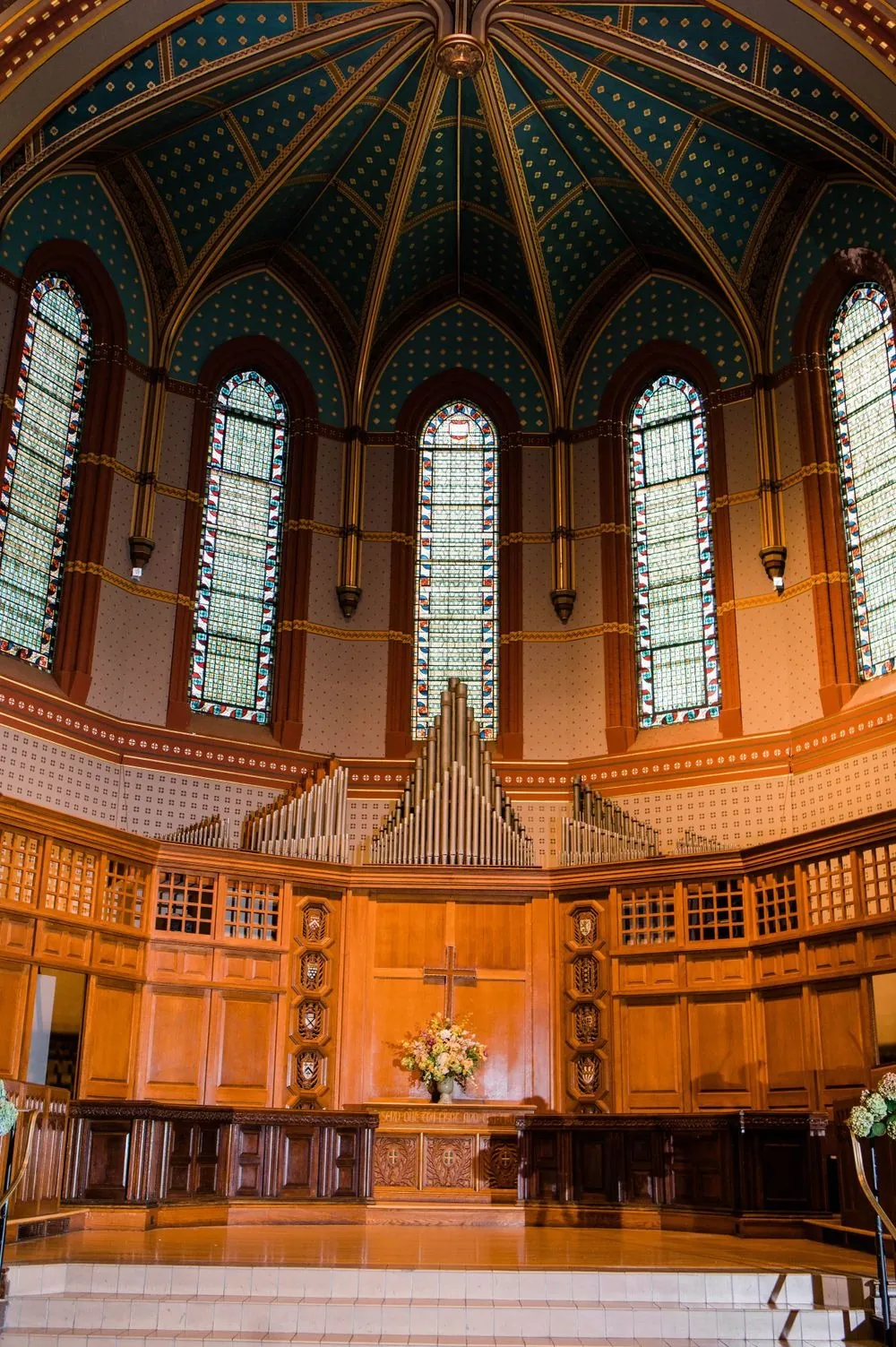 The painted dome and stained glass windows of Battell Chapel above rows of oak pews