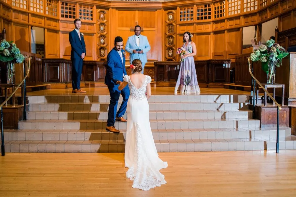 The bride walks toward the front of the chapel as the groom waits at the top of the steps