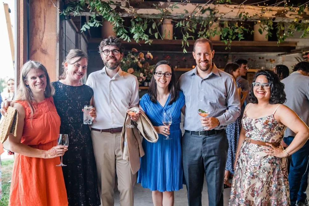 Guests in summer dresses and linen smile together during cocktail hour