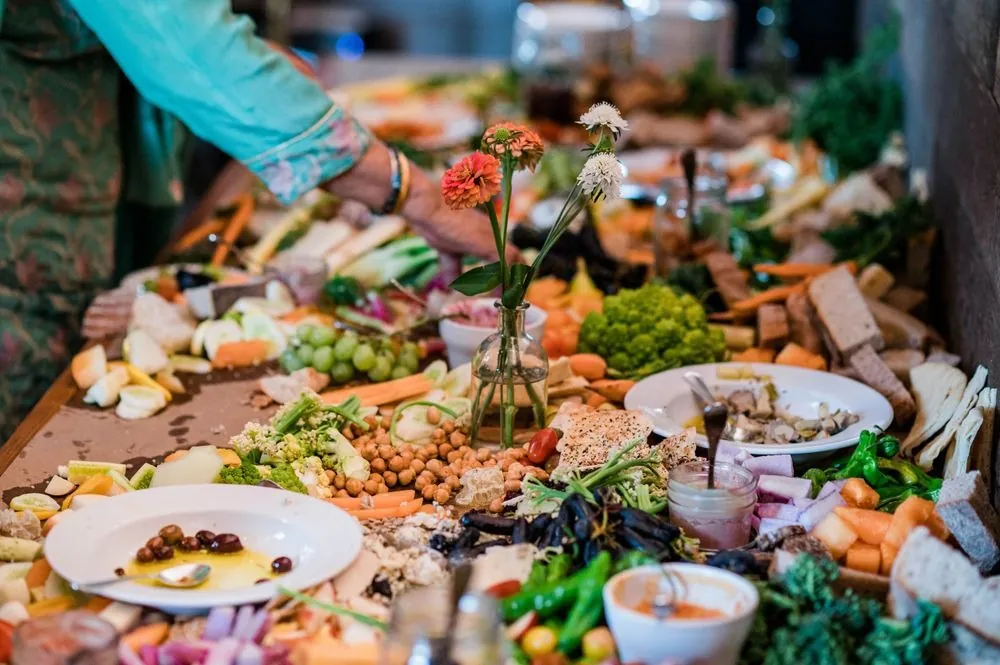 A long grazing table piled with bread, cheese, fruit, and flowers