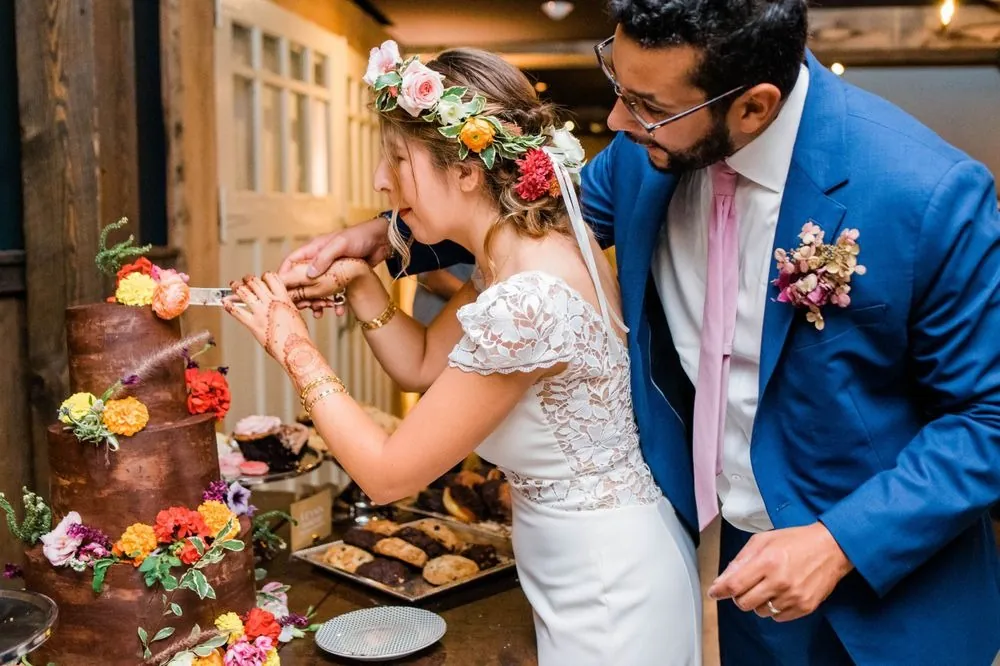The couple cut a chocolate cake decorated with fresh orange and pink flowers
