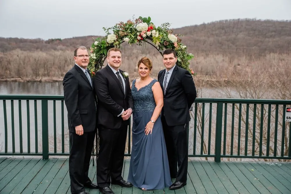 The small wedding group waits at the arch on the deck above the river