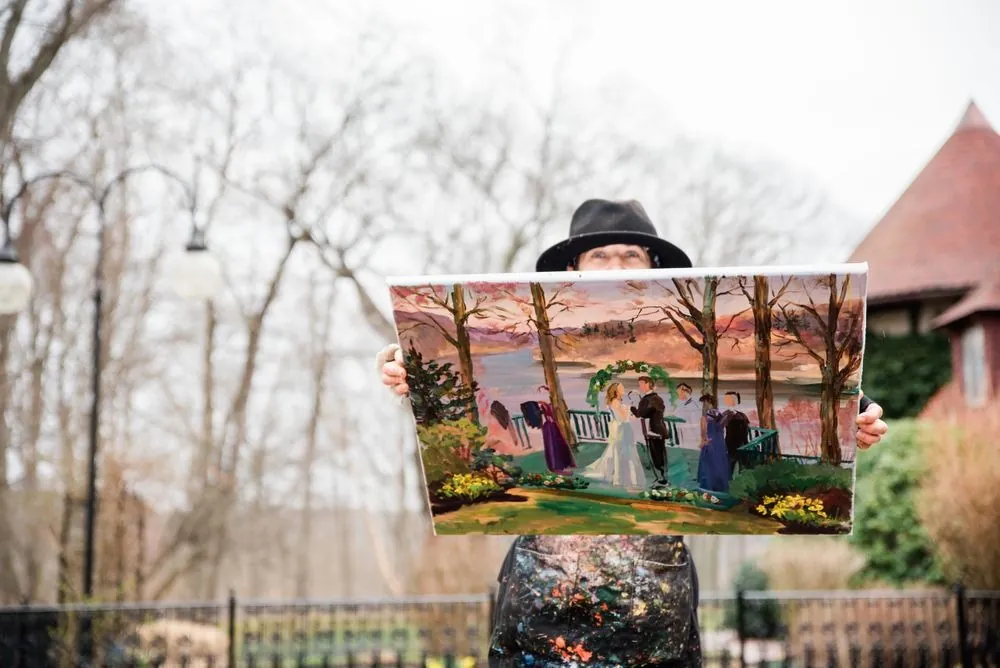 A painter holds up a finished canvas of the riverside ceremony outside the castle