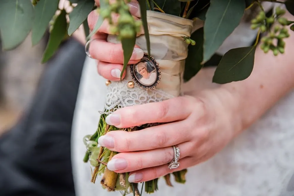 Close view of the bride's engagement ring on her hand wrapped around the bouquet