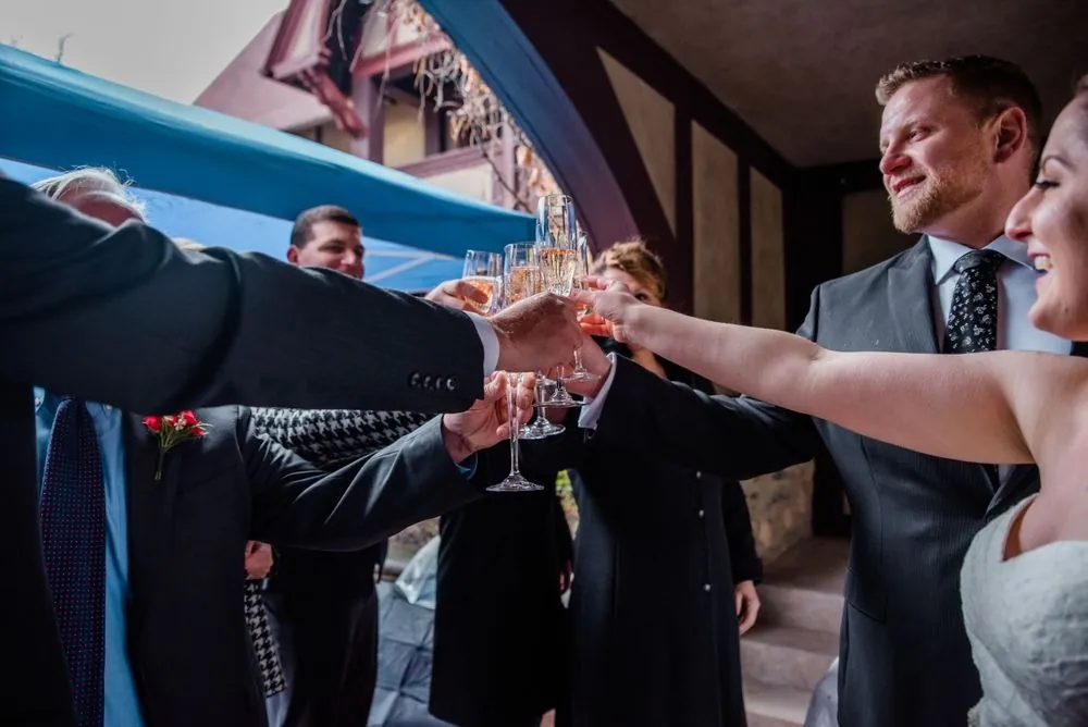 Guests raise champagne glasses in a toast with the couple indoors