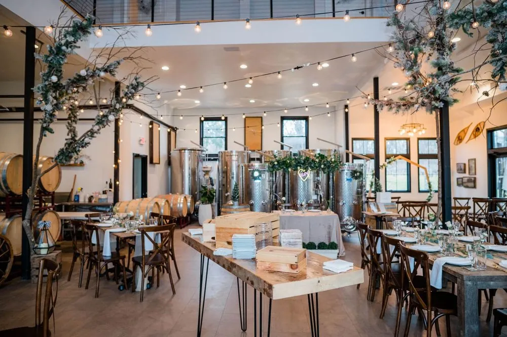 The tasting room set for dinner, long tables running past steel wine tanks