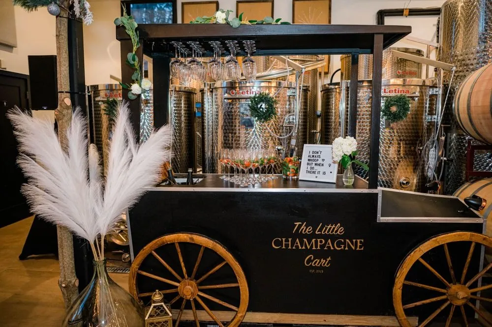 A small black champagne cart with wooden wheels and dried pampas in the tasting room