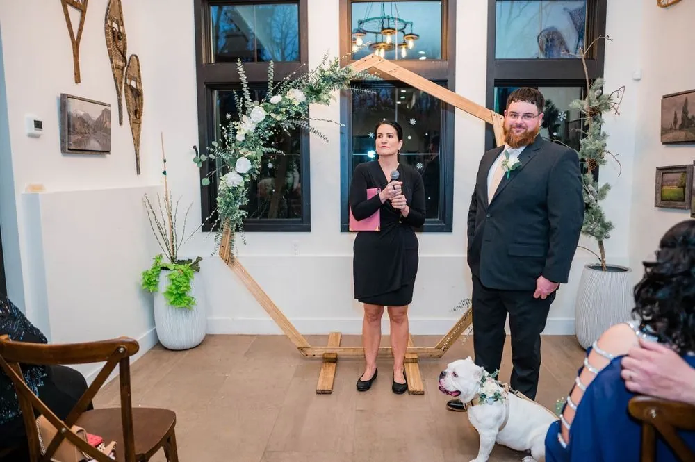 The officiant and groom wait under the hexagon arch, a bulldog at his feet
