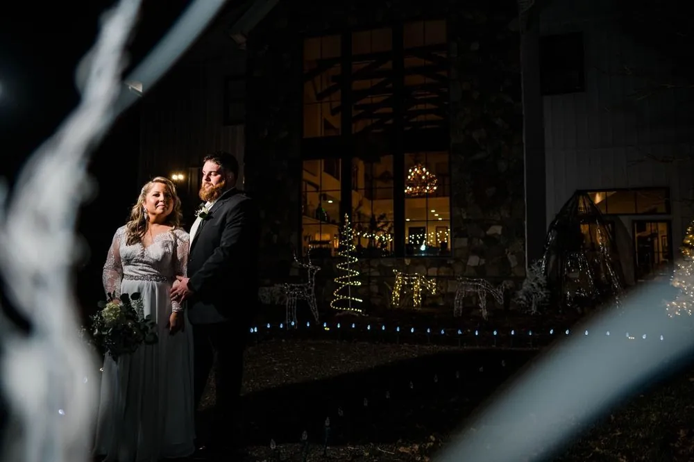 The couple outside at night, framed by blurred lights, the tall lit windows behind them