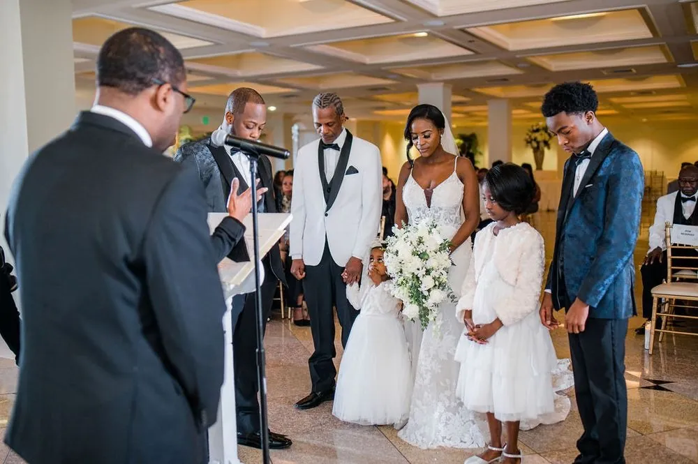 The officiant prays over Taria, Franklin and their children, every head bowed before the vows
