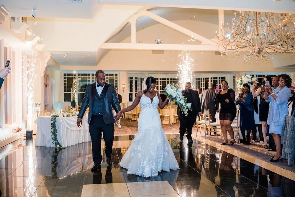 Taria and Franklin enter the reception hand in hand as sparkler fountains flare behind them