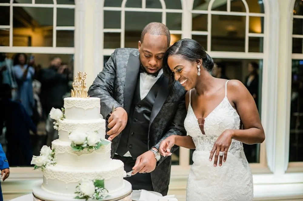 Franklin and Taria cut the cake together, laughing, as guests watch from behind