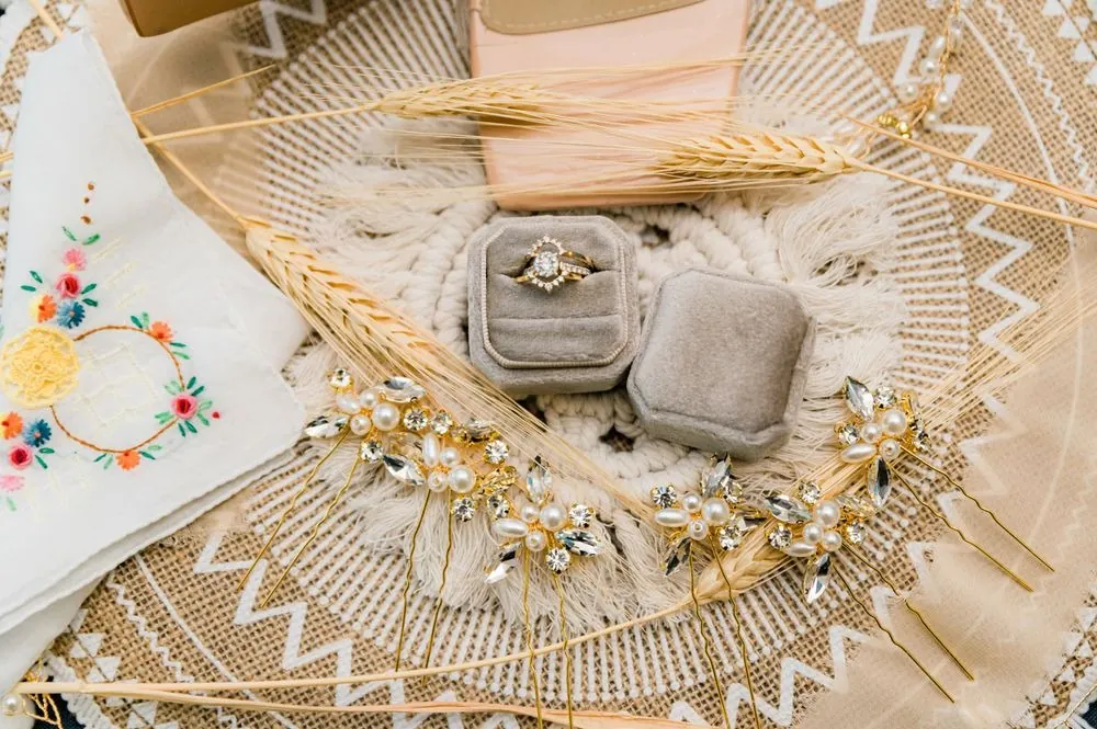 Wedding rings in a gray velvet box on a woven rattan tray with dried flowers