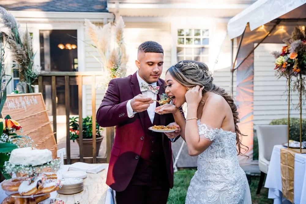 Tyler feeds Tatiana a bite of cake as she laughs and covers her face